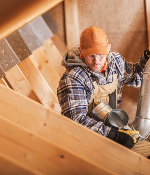 Caucasian Professional Air Quality Technician Installing Home Ventilation Elements Keeping Piece of Metal Pipe in His Hand.